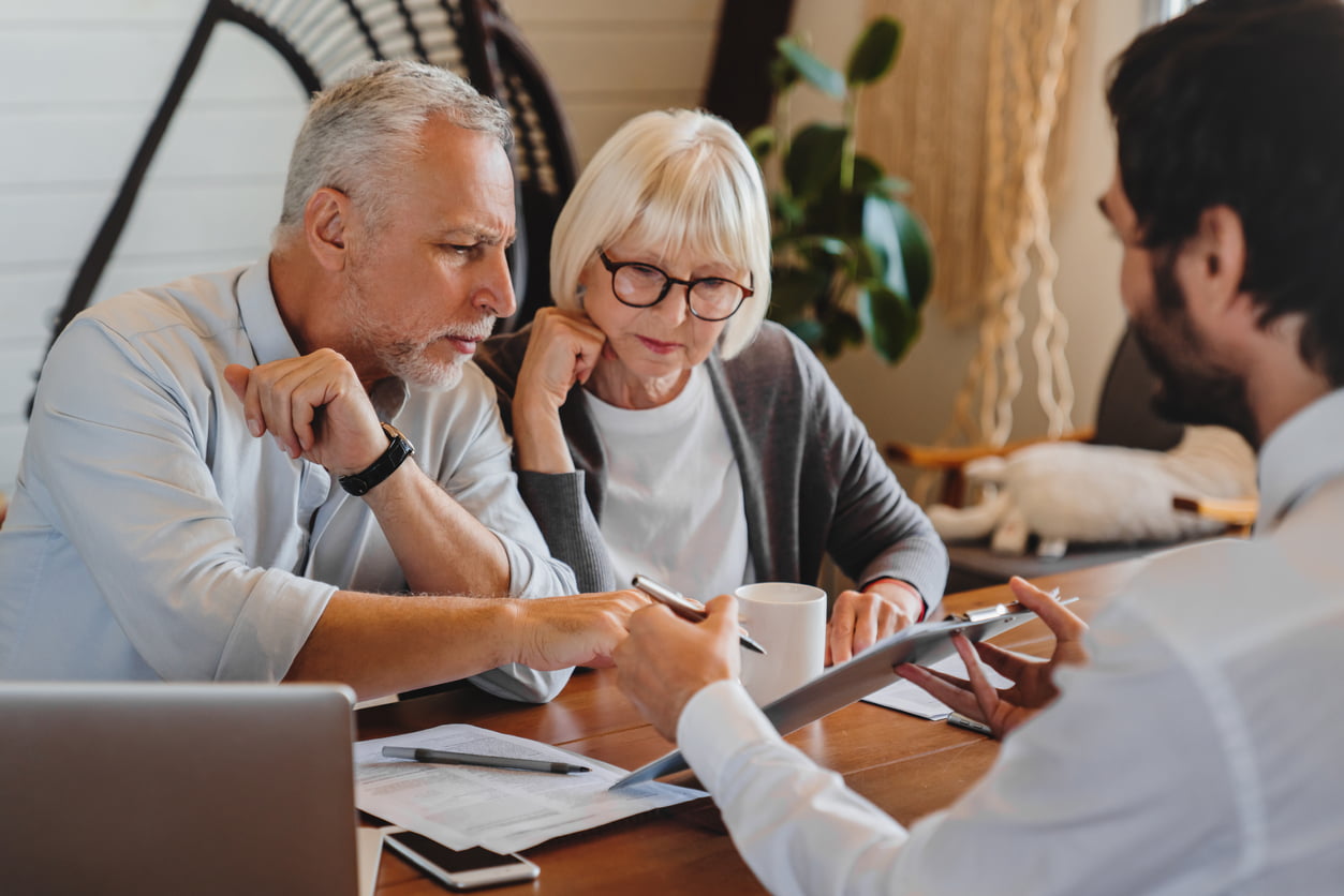 A couple reviewing paperwork with an adviser at their kitchen table